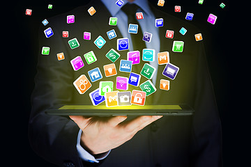 Image showing Businessman holding a tablet pc with mobile applications icons on virtual screen . Internet and business concept.