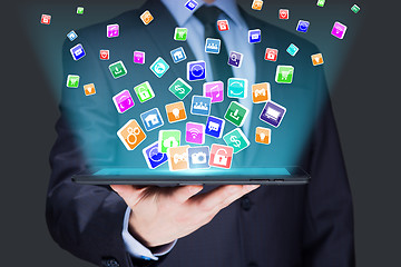 Image showing Businessman holding a tablet pc with mobile applications icons on virtual screen . Internet and business concept.