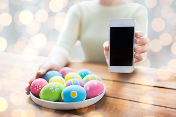 Image showing close up of hands with easter eggs and smartphone