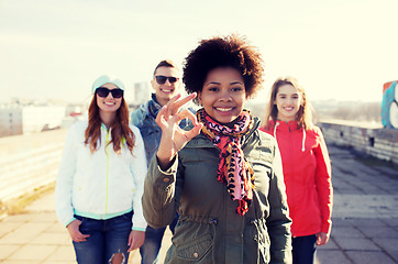 Image showing happy teenage friends showing ok sign on street