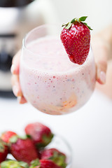 Image showing close up of hand holding glass with fruit shake