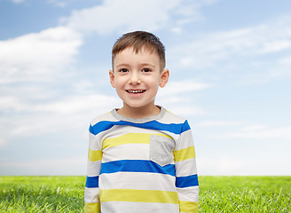 Image showing smiling little boy over blue sky and green field