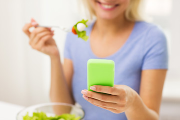 Image showing close up of woman with smartphone eating salad