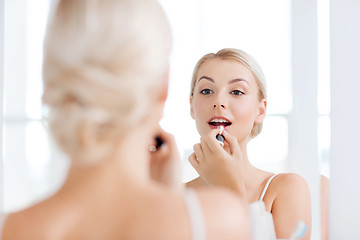 Image showing woman with lipstick applying make up at bathroom