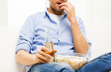 Image showing close up of man with popcorn and beer at home