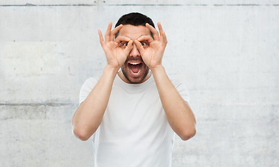 Image showing man making finger glasses over gray background