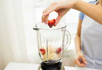 Image showing close up of woman with blender making fruit shake