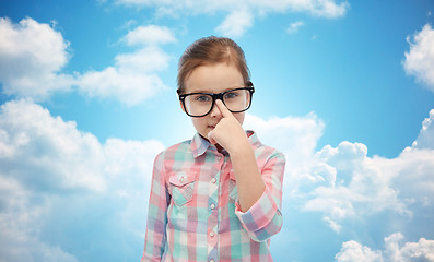 Image showing happy little girl in eyeglasses over blue sky
