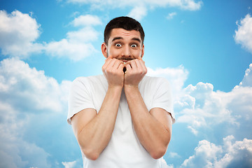 Image showing scared man in t-shirt over blue sky background