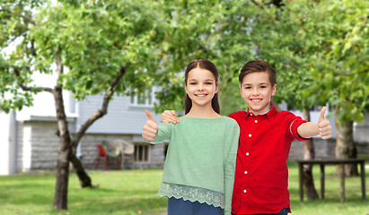 Image showing happy boy and girl showing thumbs up over backyard