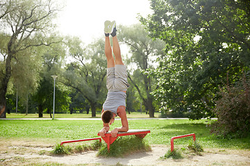 Image showing young man exercising on bench at summer park