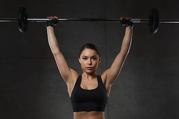 Image showing young woman flexing muscles with barbell in gym