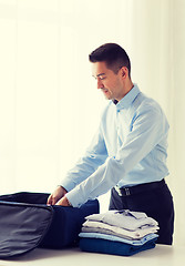 Image showing businessman packing clothes into travel bag