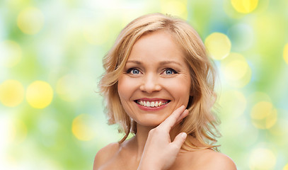 Image showing smiling woman with bare shoulders touching face