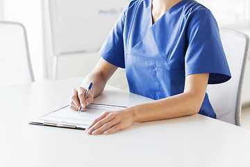 Image showing close up of doctor or nurse writing to clipboard