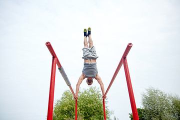 Image showing young man exercising on parallel bars outdoors