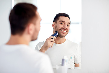 Image showing man shaving beard with trimmer at bathroom