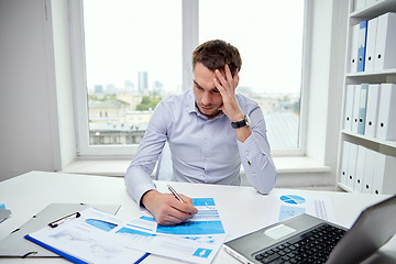 Image showing stressed businessman with papers in office