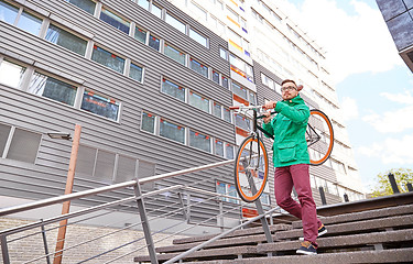 Image showing young hipster man carrying fixed gear bike in city