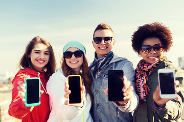 Image showing smiling friends showing blank smartphone screens