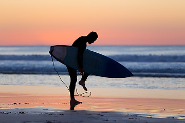 Image showing Silhouette of surfer on beach with surfboard.