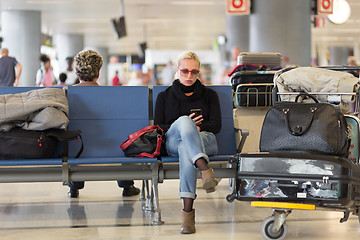 Image showing Female traveler using cell phone while waiting on airport.