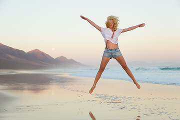 Image showing Young beautiful woman jumping in the beach.