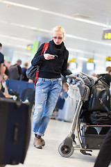 Image showing Female traveler using cell phone while waiting on airport.