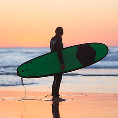 Image showing Silhouette of surfer on beach with surfboard.