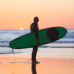 Image showing Silhouette of surfer on beach with surfboard.