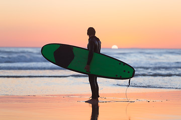 Image showing Silhouette of surfer on beach with surfboard.