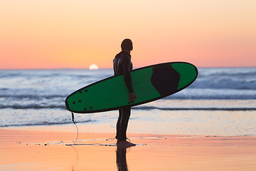 Image showing Silhouette of surfer on beach with surfboard.