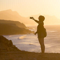 Image showing Woman snaping photo of La Pared beach in sunset.