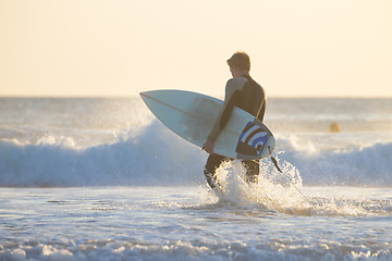 Image showing Silhouette of surfer on beach with surfboard.