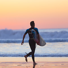 Image showing Silhouette of surfer on beach with surfboard.