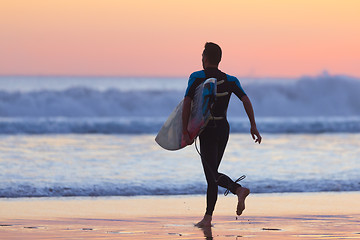 Image showing Silhouette of surfer on beach with surfboard.