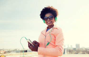 Image showing happy young woman with smartphone and headphones