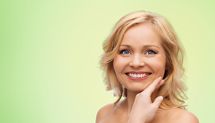 Image showing smiling woman with bare shoulders touching face