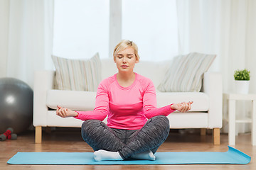 Image showing happy woman stretching leg on mat at home