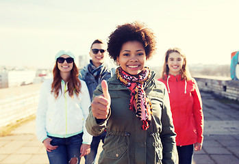 Image showing happy teenage friends showing thumbs up on street