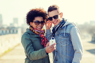 Image showing smiling couple with smartphone and earphones