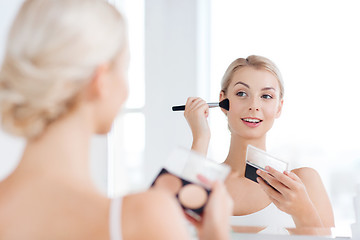 Image showing woman with makeup brush and foundation at bathroom