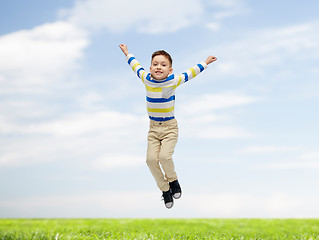 Image showing happy little boy jumping over blue sky and grass