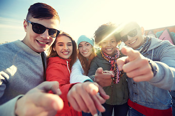 Image showing happy teenage friends pointing fingers on street