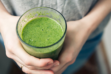 Image showing woman holding a glass of green smoothie