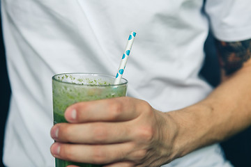 Image showing Man holding a glass of green smoothie