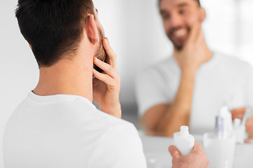 Image showing close up of man applying cream to face at bathroom