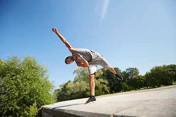 Image showing sporty young man jumping in summer park