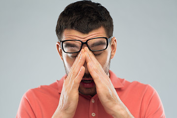 Image showing tired man in eyeglasses rubbing eyes