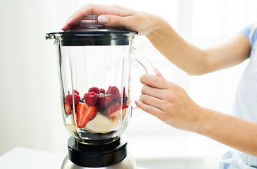 Image showing close up of woman with blender making fruit shake